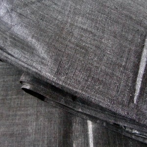 May include: Close-up of a black fabric with a woven texture. The fabric is folded over itself, creating a layered effect.