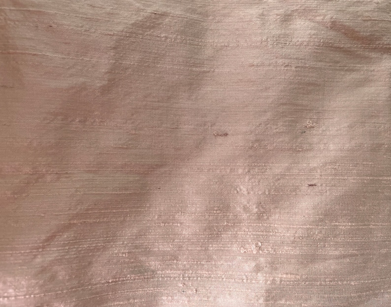 May include: A close-up of a smooth, light brown fabric with a subtle sheen. The fabric has a woven texture with fine lines running horizontally.