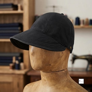 Può includere: Un cappellino da baseball nero a tinta unita con corona strutturata e visiera ampia e curva con impunture a vista. Il cappellino presenta un piccolo bottone metallico sul pannello laterale, offrendo un'estetica pulita ed essenziale.