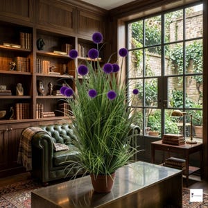 Puede incluir: Una planta en maceta con vibrantes flores esféricas moradas y largas hojas a rayas verdes y blancas. La planta está sobre una mesa de centro metálica en una habitación con un sofá de cuero verde y una gran ventana.