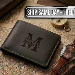 May include: A dark brown leather bifold wallet featuring a laser-engraved monogram of the letter M with the name MORGAN centered across it. The wallet is positioned on a vintage map surface alongside a gold-toned compass and a wristwatch.