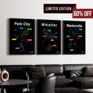 May include: Three black framed wall art prints featuring maps of Park City, Whistler, and Bentonville. Each map has a black background with white text, colorful trail outlines, and labeled markers. A red banner in the corner reads LIMITED EDITION 60% OFF.