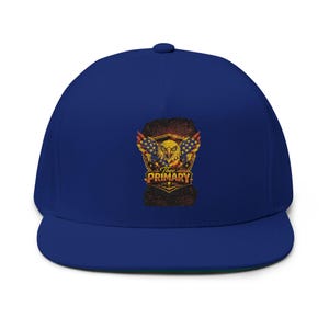 May include: A royal blue flat-brimmed baseball cap featuring an embroidered design. The design includes an eagle, American flags, and the text "The PRIMARY" in gold and red. The cap has a structured fit and a flat brim.