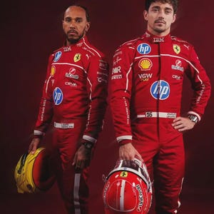 Könnte beinhalten: Zwei Personen in roten Rennanzügen mit weißen Akzenten, die Helme halten. Ein Helm ist gelb und schwarz, der andere rot mit weißen Streifen. Die Anzüge zeigen Sponsorenlogos und das Ferrari-Emblem.