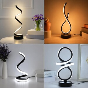May include: A collection of four LED table lamps featuring black bases and curved, spiraling or circular light-emitting structures. Each lamp emits a bright white or warm glow, showcasing distinct geometric shapes including spirals, loops, and infinity-like designs.