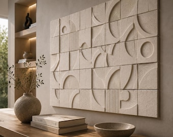 Op de afbeelding: Een rechthoekig wandkunstwerk bestaande uit beige vierkante tegels met verhoogde geometrische reliëfpatronen, waaronder cirkels, halve cirkels en verticale lijnen met een getextureerde, matte afwerking op een neutrale muur.
