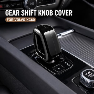 May include: A glossy black gear shift knob cover for a Volvo XC60. The cover is designed to fit over the existing gear shift lever. The image also shows the car's interior, including the start/stop button and gear selector.