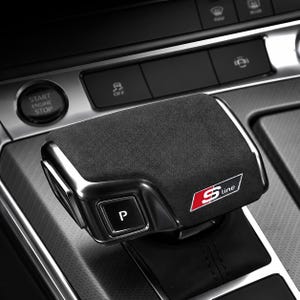 May include: A black suede gear shifter knob featuring a metallic silver trim and a prominent S-line logo in red and white. The gear selector includes a square button labeled with the letter P, set against a dark automotive interior console.