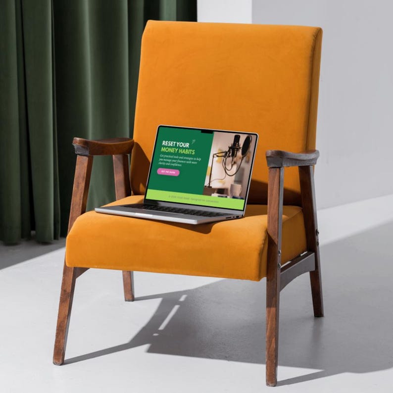 May include: An orange velvet armchair with wooden armrests and legs. A laptop displaying the text "RESET YOUR MONEY HABITS" sits on the chair. The screen shows a microphone and other objects. A green curtain is in the background.