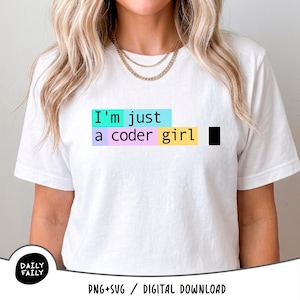 May include: A white short-sleeved t-shirt featuring the text "I'm just a coder girl" printed in black. The text is highlighted by rectangular blocks of cyan, light purple, pink, and yellow, with a small black square at the end of the line.