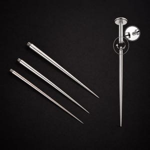 May include: A set of four silver-colored metal piercing tapers with a smooth, tapered design. Three tapers are arranged diagonally, while one is shown vertically with a circular inset detail demonstrating the threaded screw-on mechanism.