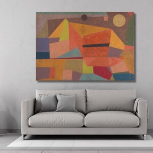 May include: Abstract geometric painting with a warm color palette of orange, yellow, and red, accented by blue and purple shapes. The artwork features a black horizontal line and a circular shape resembling a sun. The painting is displayed above a gray sofa.