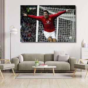 Puede incluir: Un cuadro rectangular de pared que muestra a un futbolista con una camiseta roja de manga larga con el logotipo de Vodafone y pantalones cortos blancos, con los brazos extendidos en celebración frente a una red de portería.