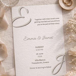 Puede incluir: Una invitación de boda con los nombres "Emma & James" en escritura elegante. La invitación incluye la fecha, hora y lugar: Villa Bianca, Tesalónica, Grecia. El diseño presenta elementos decorativos y el texto "Cena y baile a continuación."