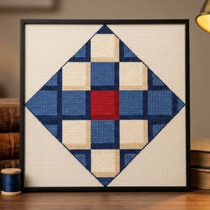 Peut inclure: Une broderie au point de croix encadrée présentant un motif géométrique en losange composé de carrés crème, bleu foncé et bleu moyen, avec un carré rouge uni unique positionné au centre du motif, le tout sur un fond en tissu de couleur crème.