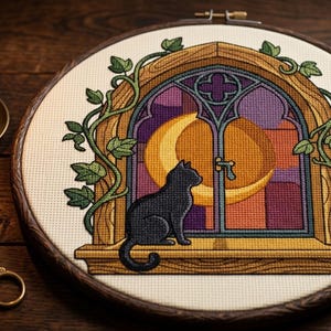 Peut inclure: Une broderie au point de croix dans un tambour en bois circulaire représentant un chat noir assis sur un rebord de fenêtre. La fenêtre possède un cadre en bois, des vitraux violets et orange, et un grand croissant de lune jaune. Du lierre vert grimpe.
