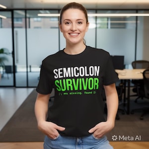 Puede incluir: Camiseta negra con las palabras "SEMICOLON SURVIVOR" en blanco y verde. Debajo del texto está la frase "// was missing. found it!". La camiseta es de cuello redondo.