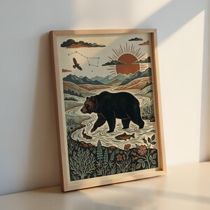 May include: Framed art print featuring a bear walking in a river, with fish, mountains, and a sunset. The artwork has a vintage style with a color palette of browns, greens, and oranges. An eagle and constellation are in the sky.