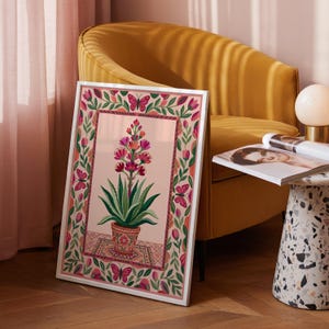 Peut inclure: Une affiche encadrée représentant une plante en pot avec des fleurs roses et oranges, des feuilles vertes et une bordure décorative avec des papillons et des éléments floraux. L'œuvre est posée sur un fond rose clair.