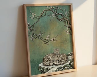 Puede incluir: Impresión artística enmarcada que representa dos leopardos de las nieves descansando sobre una formación rocosa nevada. La obra de arte tiene un fondo verde y turquesa con una rama de árbol con flores blancas. El marco es de madera clara.