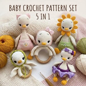 May include: A set of five crocheted baby toys featuring duck-like figures with various accessories, including a pink overall outfit, a yellow sun-shaped hat, a green bonnet, and a purple skirt, alongside balls of yarn and a crochet hook.