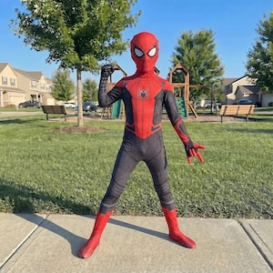 Op de afbeelding: Een rood en zwart Spider-Man kostuum. Het kostuum heeft een rood masker met witte ooglenzen, een rode borst en benen en zwarte armen en torso. Het pak heeft een spinnenembleem op de borst.