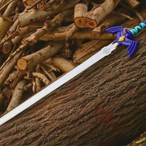 Puede incluir: Una espada de r&eacute;plica con una hoja larga de color plateado y un emblema triangular cerca de la empu&ntilde;adura. La empu&ntilde;adura es azul oscuro con guardas en forma de ala, un diamante dorado central y un mango envuelto en bandas azul turquesa y azul.