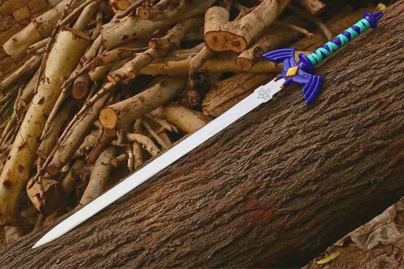 Puede incluir: Una espada de r&eacute;plica con una hoja larga de color plateado y un emblema triangular cerca de la empu&ntilde;adura. La empu&ntilde;adura es azul oscuro con guardas en forma de ala, un diamante dorado central y un mango envuelto en bandas azul turquesa y azul.