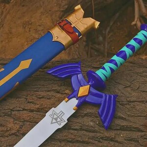 Puede incluir: Una espada azul y dorada con su funda a juego. La espada presenta una guarda morada con extensiones en forma de ala, un mango envuelto en azul cerceta y morado, y una hoja plateada grabada con un s&iacute;mbolo triangular. La funda tiene detalles dorados.