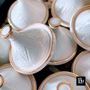 Op de afbeelding: Een witte keramische mok met een zwarte handgreep en de tekst "But First, Coffee" in een vetgedrukte, zwarte letter. De mok staat tegen een vage achtergrond, wat een gezellige setting suggereert.