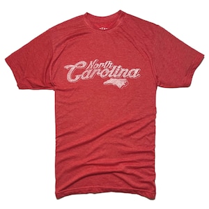 K&ouml;nnte beinhalten: Rotes T-Shirt mit dem Text "North Carolina" in verblichener wei&szlig;er Schrift und einer wei&szlig;en Umrisslinie des Bundesstaates. Das Shirt hat kurze &Auml;rmel und einen Rundhalsausschnitt.