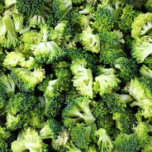 May include: Close-up shot of fresh, chopped broccoli florets. The image showcases a vibrant mix of green and light green hues, highlighting the vegetable's natural texture and form. This image is ideal for culinary or health-related content.