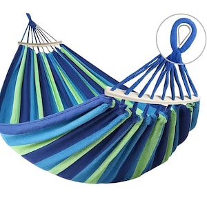 Puede incluir: Una hamaca a rayas con bandas alternas de tela azul oscuro, azul claro y verde lima. La hamaca incluye barras separadoras de madera blanca en cada extremo y cuerdas de suspensión de color azul grueso con un anillo metálico de sujeción.