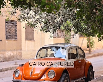 Lámina con estampado de un Volkswagen Beetle naranja de estilo vintage, escena callejera de El Cairo, arte mural minimalista en tonos neutros (descarga digital).