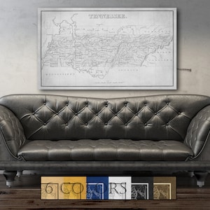 May include: A black and white vintage map of Tennessee with the title "TENNESSEE." The map is framed and hanging on a wall above a black leather sofa.