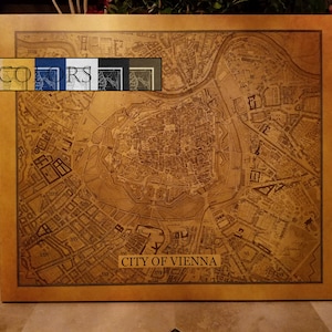 May include: A framed map of Vienna, Austria, in a sepia tone. The map details the city's layout, with the text "CITY OF VIENNA" at the bottom. The image includes a color selection guide with the text "6 COLORS".