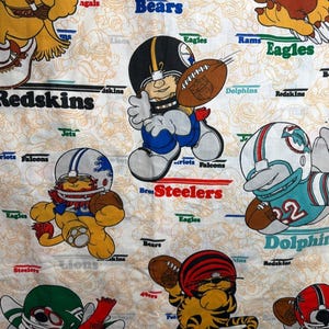 May include: White fabric featuring cartoon characters in football uniforms, each representing a different NFL team. The design includes the Bears, Steelers, Dolphins, Bengals, and others, with team names displayed.