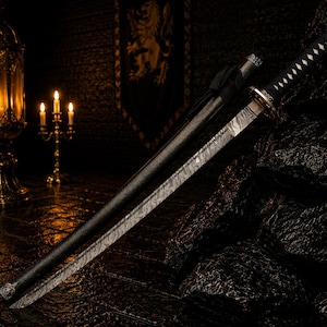 May include: A katana sword featuring a patterned Damascus steel blade and a black handle with white diamond-shaped accents. The sword is accompanied by a matching black scabbard, showcasing intricate metal fittings on the hilt and pommel.