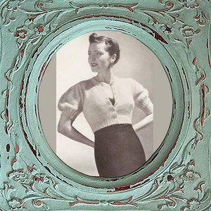 Könnte beinhalten: Ein Vintage-Foto einer Frau, die einen weißen Cardigan mit Knöpfen vorne und einen schwarzen Rock trägt. Das Foto ist in einem verwitterten, ovalen Rahmen in Teal-Farbe gerahmt.