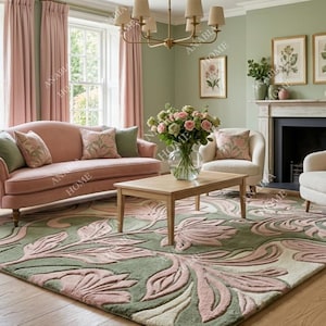 Puede incluir: Una alfombra grande rectangular con un patrón botánico en relieve y texturizado en tonos verde salvia suave y rosa empolvado. El diseño consiste en motivos florales y de hojas grandes y fluidos que crean una superficie dimensional.