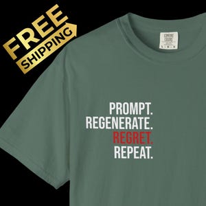以下が含まれることがあります： 左胸に白い文字で「PROMPT. REGENERATE. REPEAT.」とプリントされたセージグリーンの半袖Tシャツ。REGRET.の文字は赤色でプリントされています。クルーネックで、襟の内側にはブランドラベルが付いています。