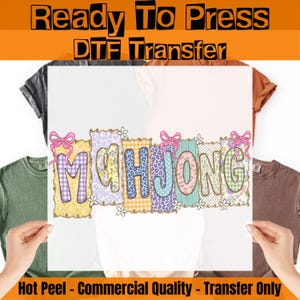 May include: A Ready To Press DTF Transfer sheet featuring the word MAHJONG in colorful, patterned block letters with pink bows and small white flowers. The design includes various textures like gingham, leopard print, and floral patterns.