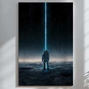 May include: A vertical wall art print depicting an astronaut standing on a dark, cratered lunar surface. A bright, vertical beam of blue light extends upward from the astronaut into the black sky, creating a stark contrast against the dark landscape.