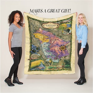 May include: A vintage-style map of the Driftless Region, printed on a soft, beige fleece blanket. The map features a compass, rivers, and other geographical details. The blanket is held by two people.