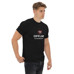 Puede incluir: Camiseta negra con el texto "OFFLINE IS THE NEW LUXURY" en blanco. Encima del texto hay un símbolo wifi rojo y blanco. La camiseta es de manga corta y está hecha de un material suave.