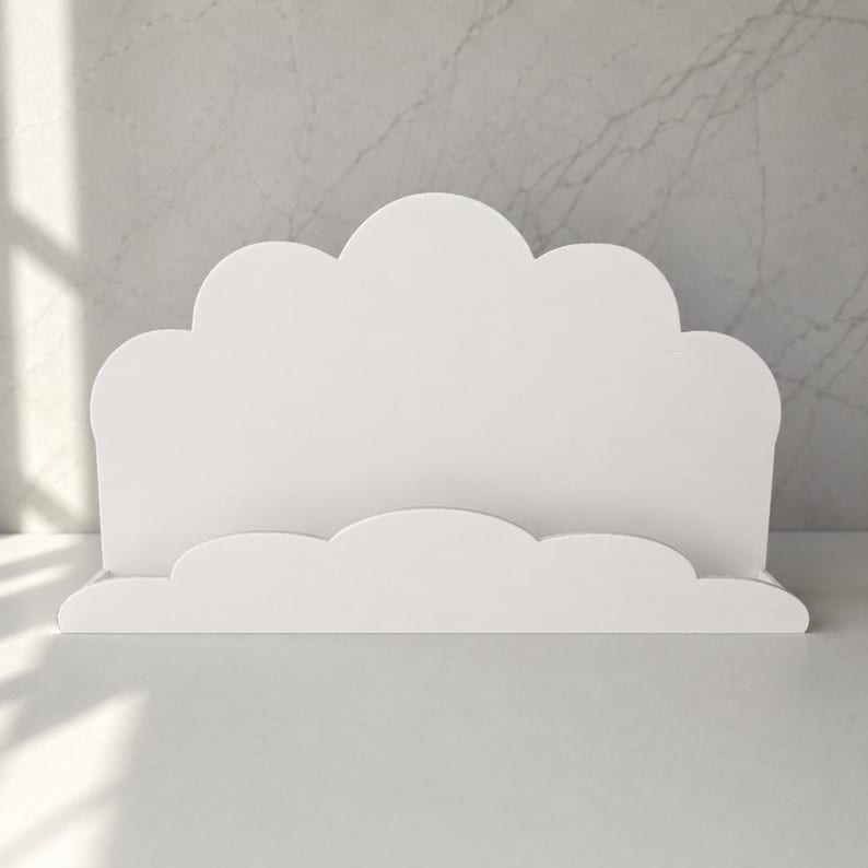 May include: A white cloud-shaped display stand featuring a smooth, matte finish. The structure consists of a tall, scalloped back panel and a shorter, matching scalloped front ledge, creating a slot for holding items in an upright position.