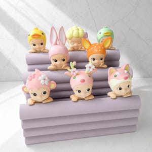 May include: A collection of small figurines, each with a unique animal-themed hat. The figurines are in various colors, including yellow, pink, orange, and green. The figurines are arranged on a stack of lavender-colored blocks.