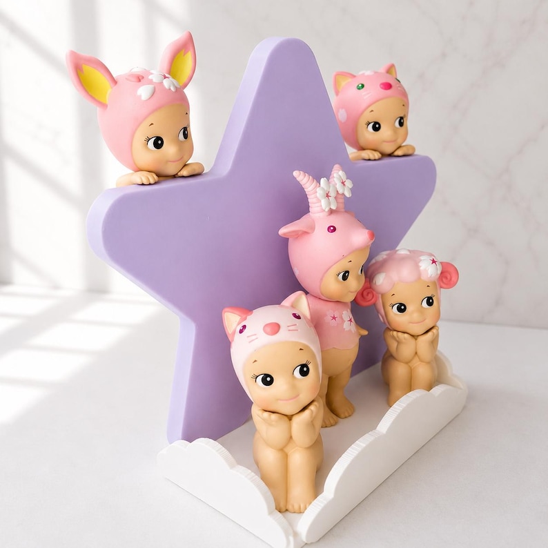 Op de afbeelding: Een verzameling kleine, grillige beeldjes, elk versierd met een unieke hoed met dierenthema. De beeldjes staan in verschillende poses, met een zacht, pastelkleurig kleurenpalet. Ze zijn gerangschikt rond een grote, paarse stervormige display.