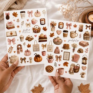 May include: Two white sticker sheets featuring autumn-themed illustrations including pumpkins, coffee cups, bows, books, candles, knitted clothing, and foliage. The text "fall kind of girl" and "grateful" is printed on the sheets in a script font.