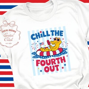 May include: White t-shirt with a graphic of an alligator in sunglasses on a float, holding an American flag popsicle. The text reads "Chill the Fourth Out." Paired with blue jeans.